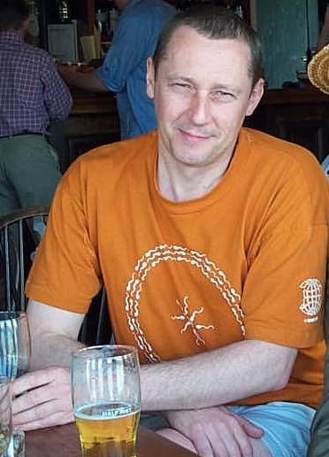 colour photograph of a man in an orange t-shirt enjoying a beer at the Trafalgar