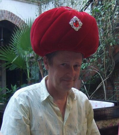 colour photograph of Kevin looking very silly wearing a large red cushion shaped hat