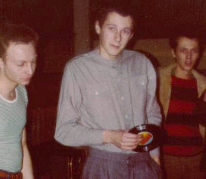 blurry colour photograph of a young man attemptinmg to look cool holding a seven inch vinyl single