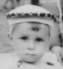 black and white blurry photograph of a small boy sitting in a pushchair staring into the camera