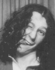 black and white photo-me booth photograph of a youth with long curly hair pulling a stupid face